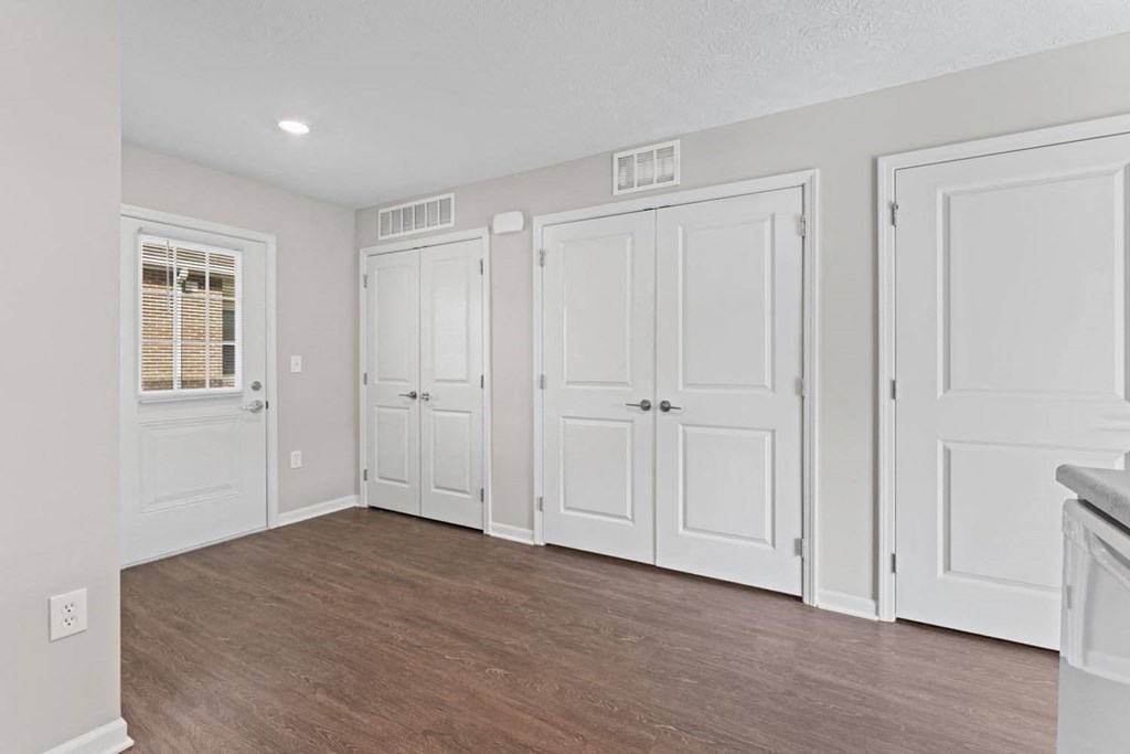 an empty living room with white doors and a window