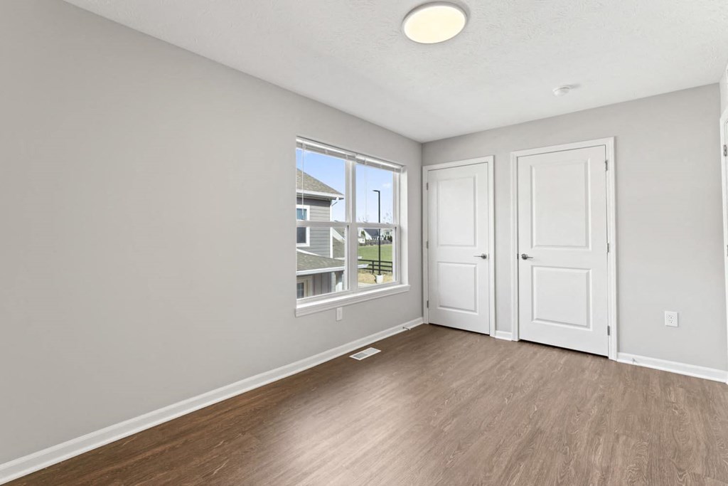 an empty living room with two doors and a window