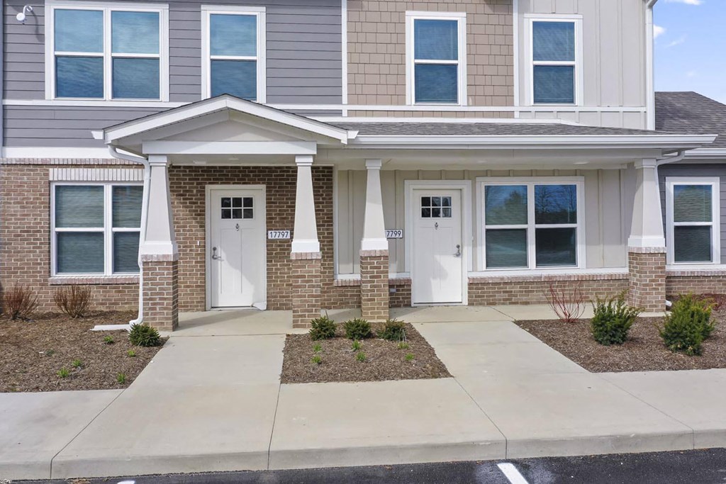 the front of a brick house with white doors and a sidewalk