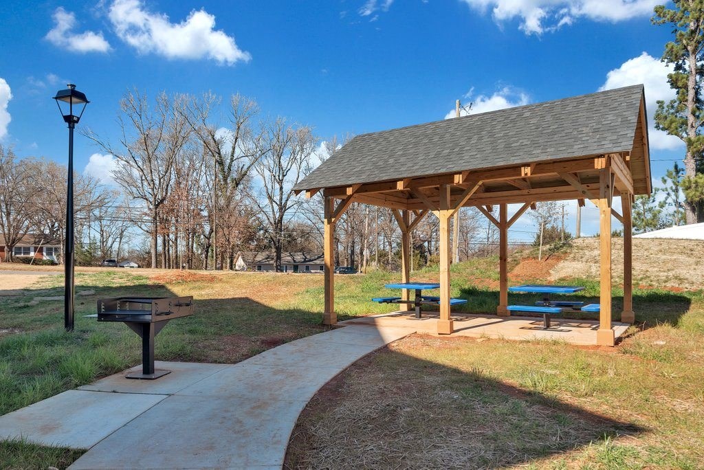 a picnic pavilion with benches and a grill in a park