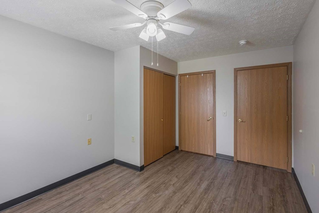 A room with a ceiling fan and wood flooring.