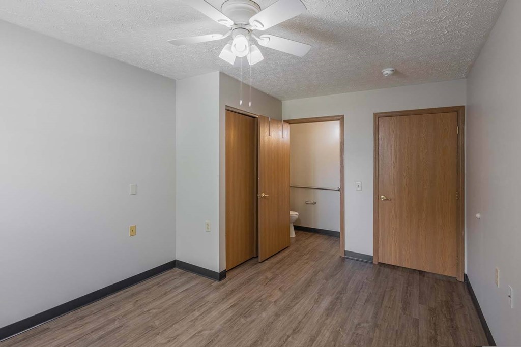 A room with a ceiling fan and three doors.