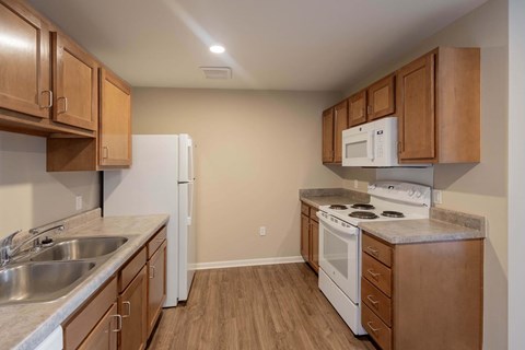 A kitchen with a white refrigerator, white microwave, and white stove.