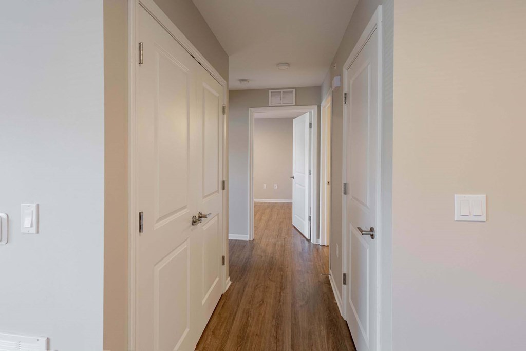 A long hallway with white walls and wood floors.
