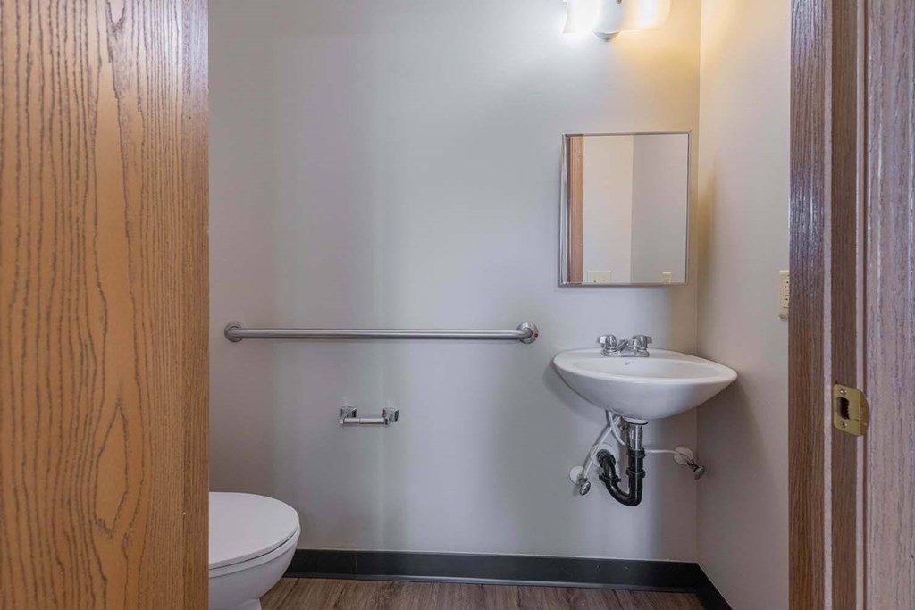 A small bathroom with a toilet, sink, and a mirror.