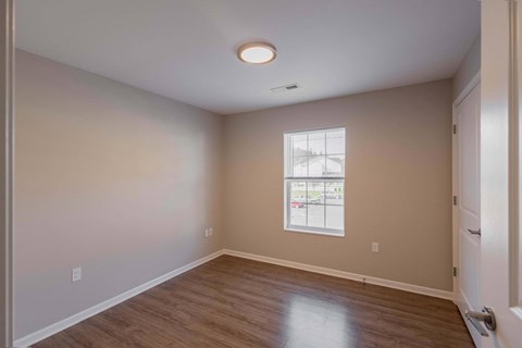 A room with a window and a wooden floor.