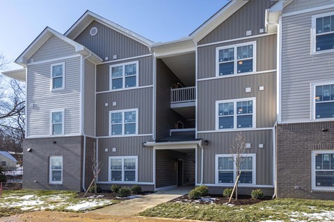 A modern two-story apartment building with a balcony on the second floor.