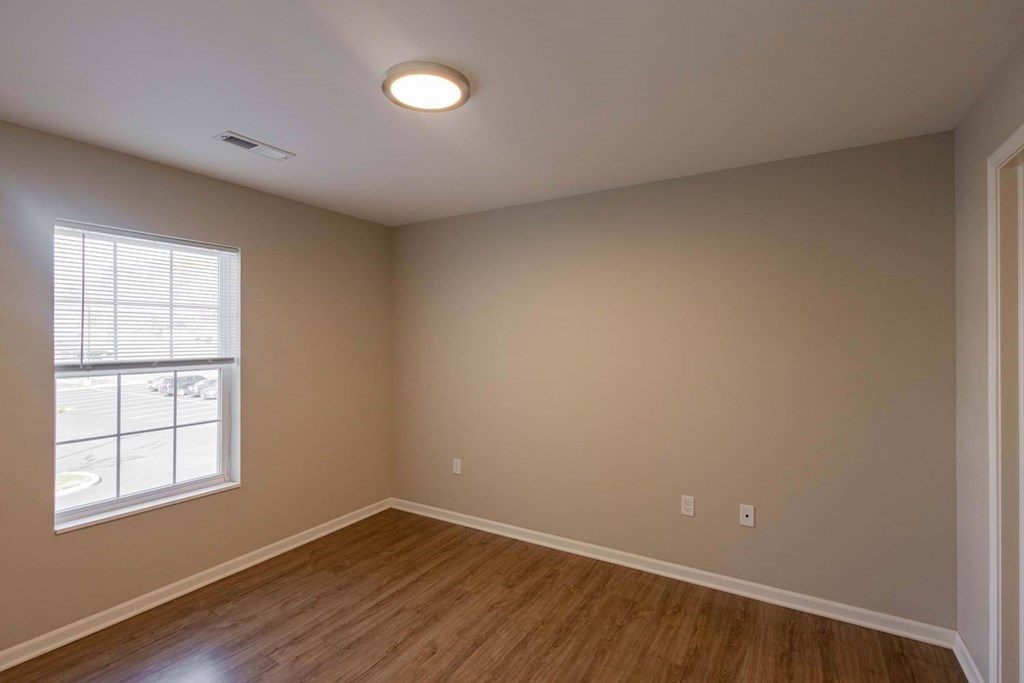 A room with a window and wooden flooring.