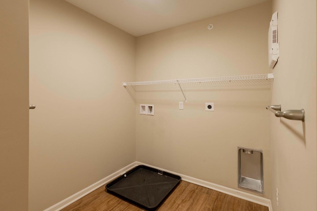 A room with a black mat on the floor and a white shelf above it.