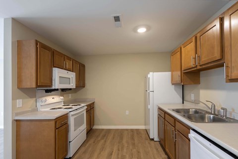A kitchen with white appliances and wooden cabinets.