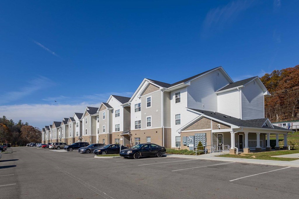A row of townhouses with a parking lot in front.