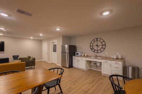 A kitchen with a table and chairs in the foreground and a refrigerator in the background.