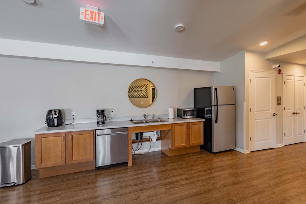 A kitchen with a refrigerator, sink, and cabinets.