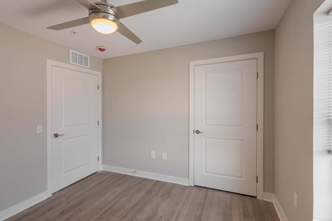 A room with a ceiling fan and two doors.