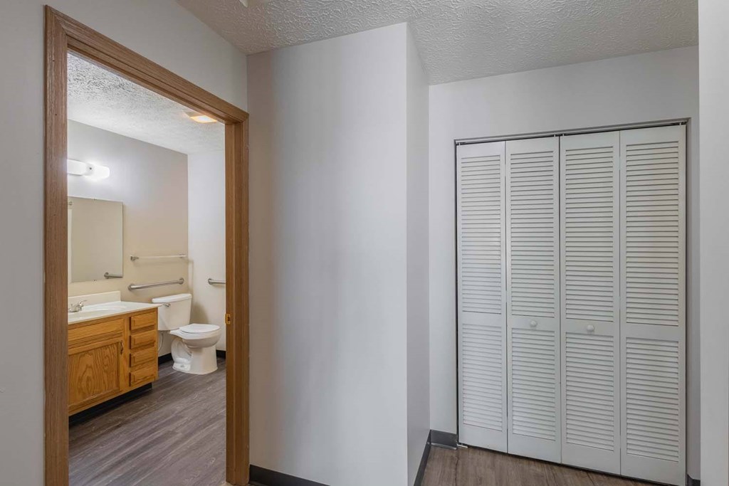 A white bathroom with a toilet, sink, and a white closet.