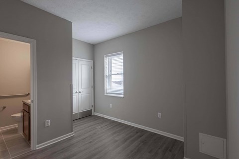 A room with a wooden floor and a window with blinds.
