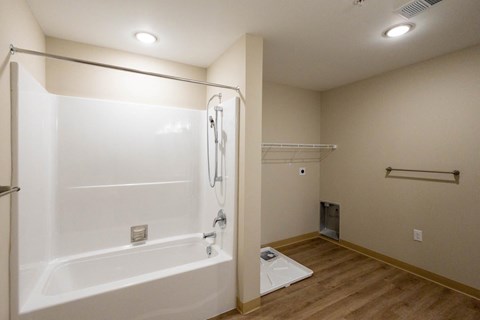 A white bathtub with a shower head and a white toilet in a bathroom.