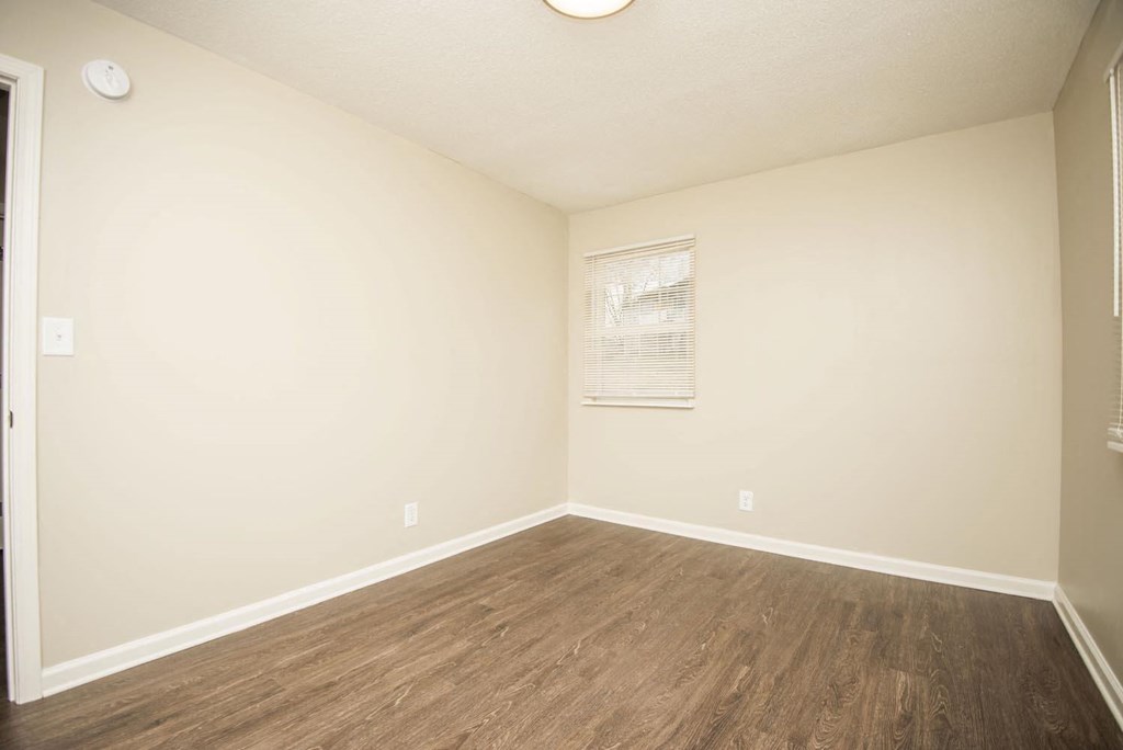 an empty room with white walls and wood floors
