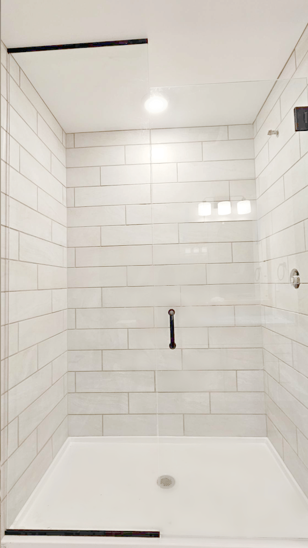 a white tiled bathroom with a tub and a shower