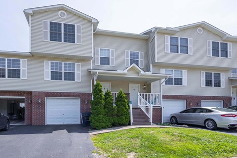 A two-story house with a garage and a car parked in front.