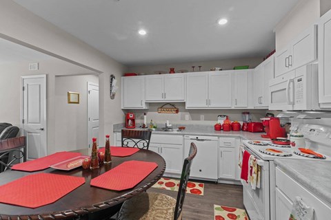 a kitchen with white cabinets and a table with red chairs