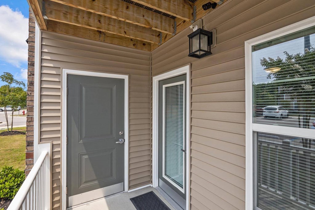 the front door of a home with a window and a porch