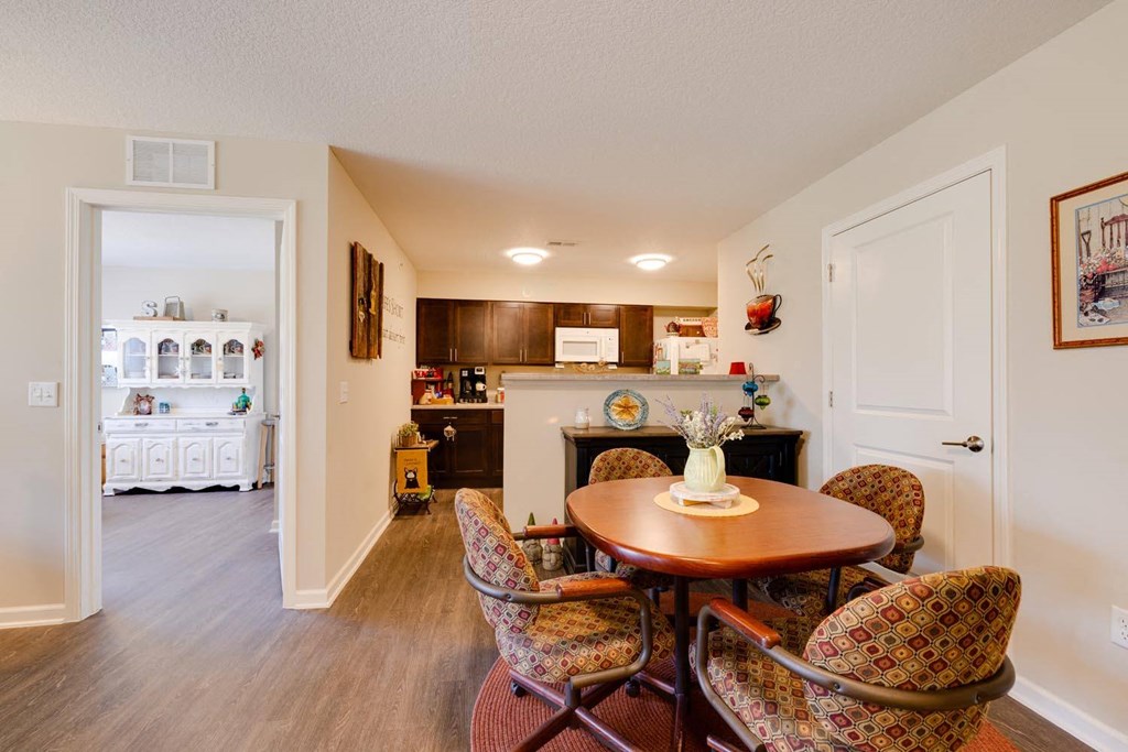 a dining area with a table and chairs and a kitchen in the background
