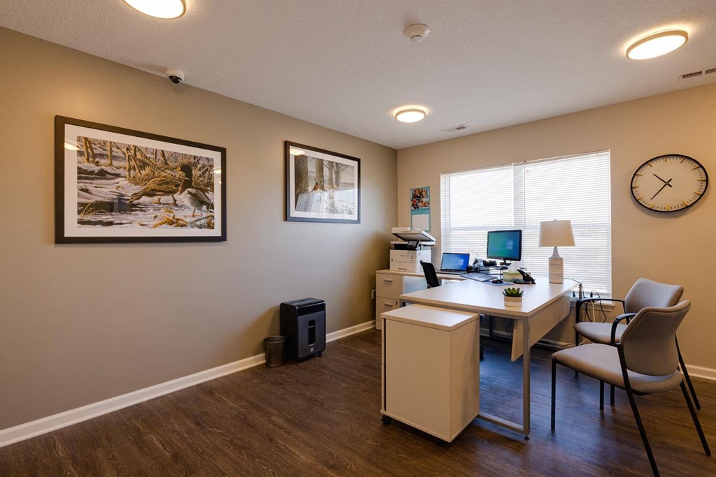 an office with a desk and two chairs and a clock on the wall