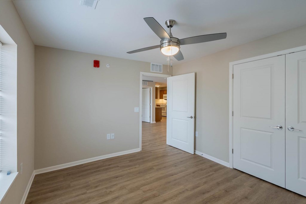 A room with a ceiling fan and wooden flooring.