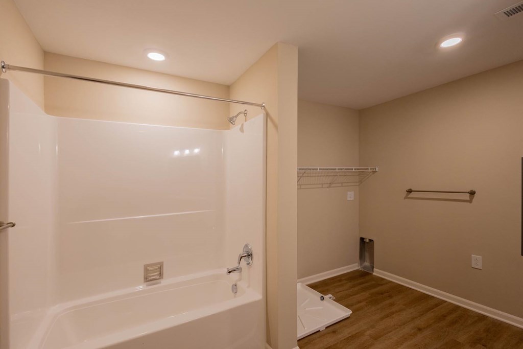 A white bathtub with a shower head and a towel bar.