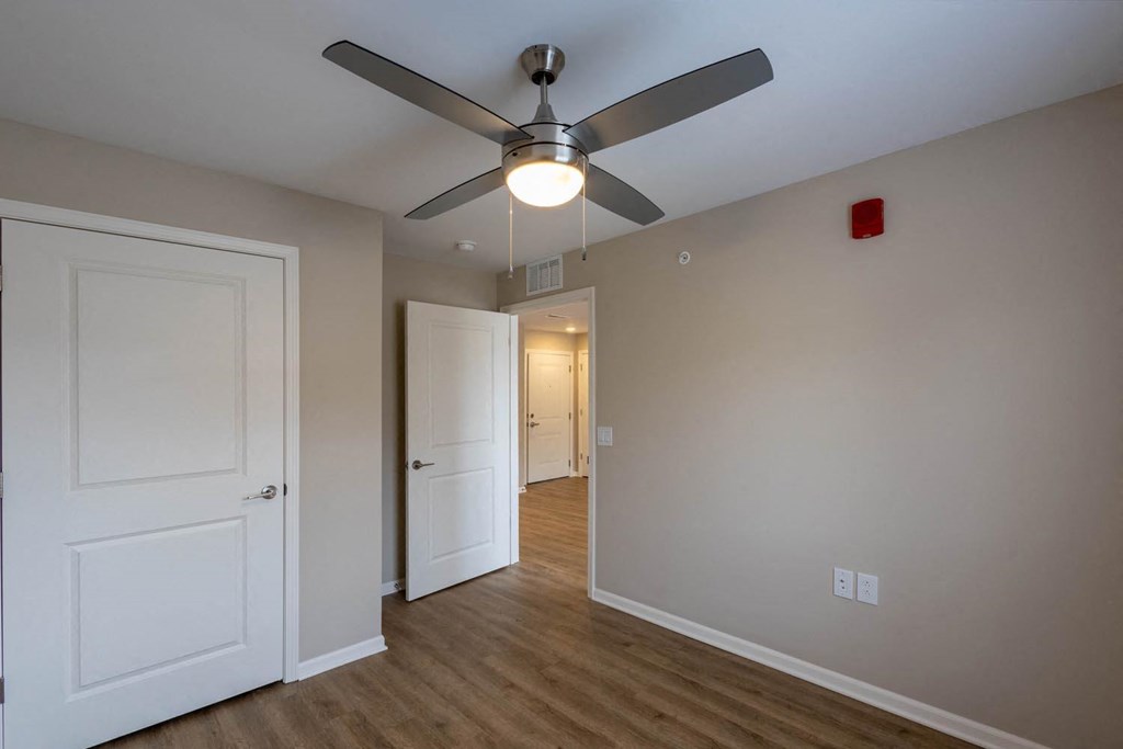 A room with a ceiling fan and two doors.