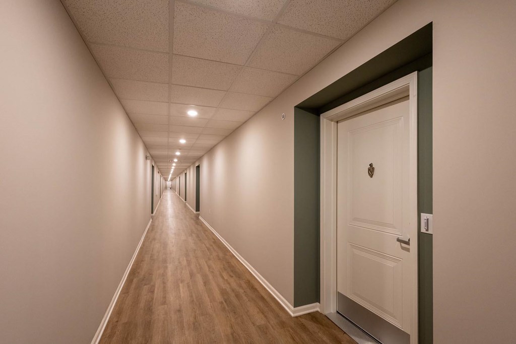 A long hallway with a white door at the end.