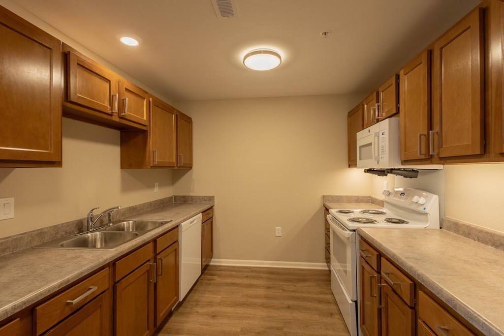 A kitchen with brown cabinets and a white stove top oven.