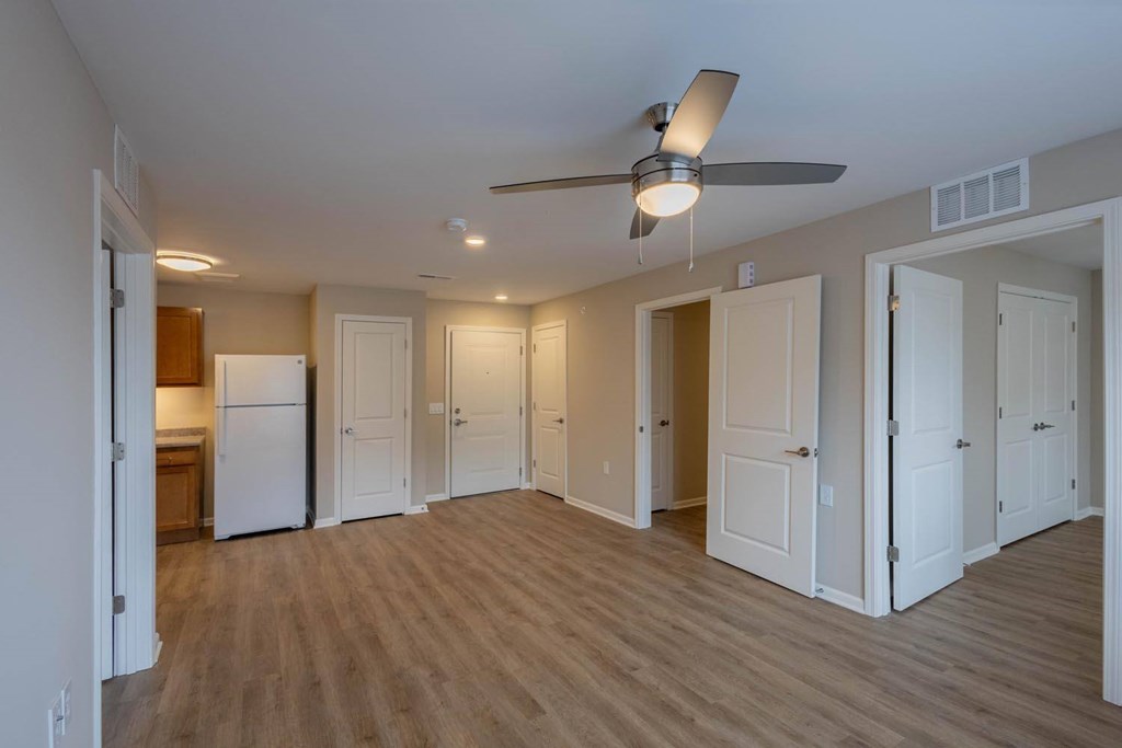 A room with a ceiling fan and wooden floors.