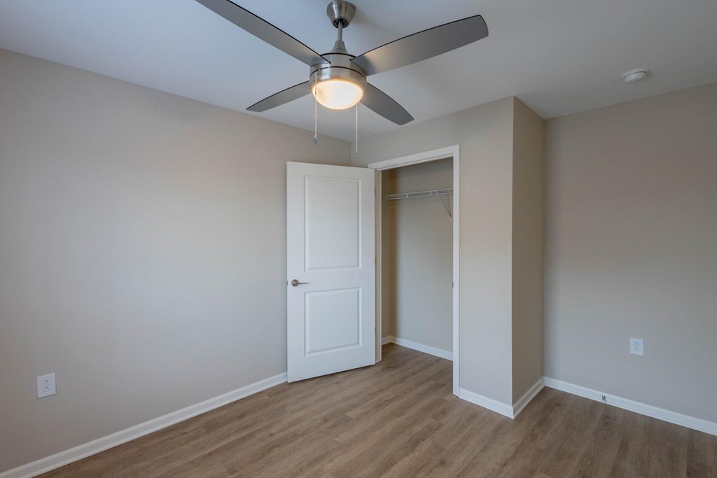 A room with a ceiling fan and a door.