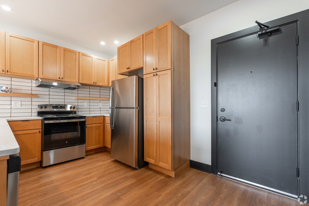 A kitchen with wooden cabinets and a stainless steel refrigerator.