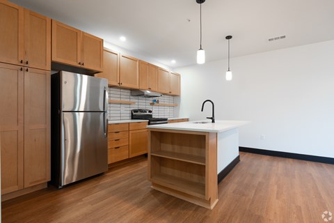 A kitchen with wooden cabinets and a stainless steel refrigerator.