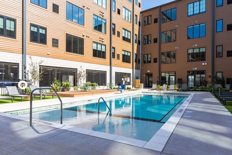 A swimming pool in front of a building with a white fence.