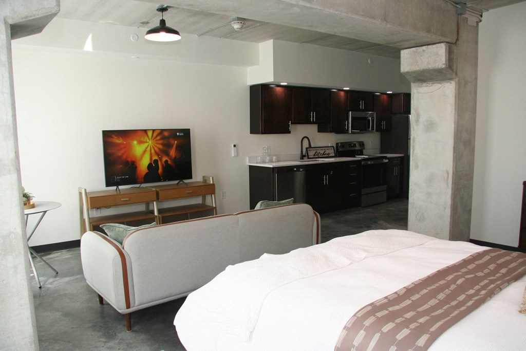 a hotel room with a couch and a bed and a kitchen