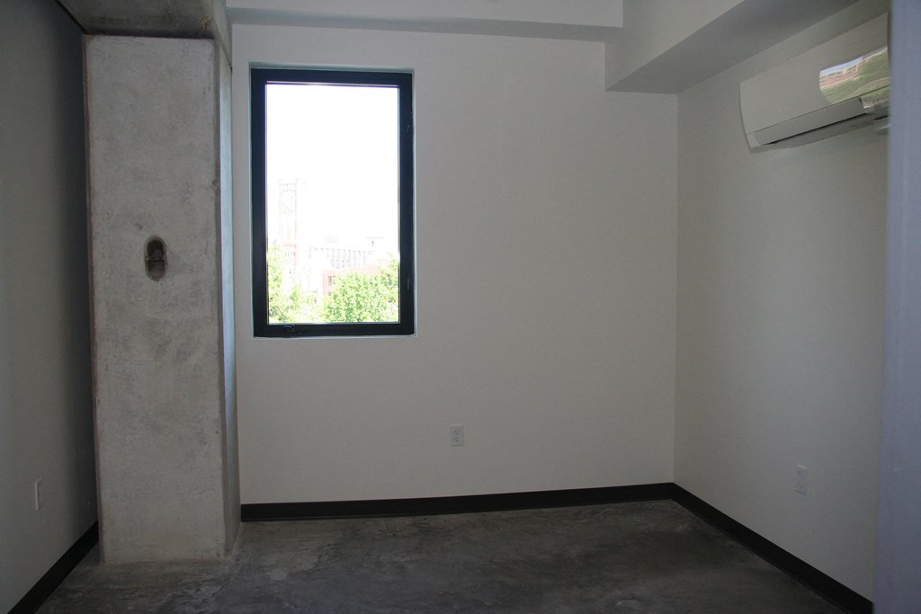an empty room with a window and a cement floor