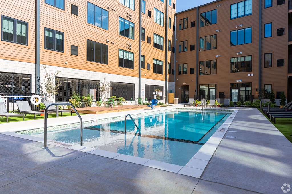 A swimming pool in front of a building with a sunny day.