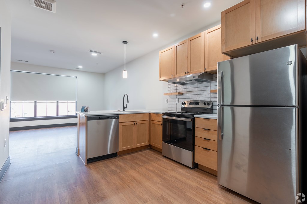 A modern kitchen with wooden floors and stainless steel appliances.