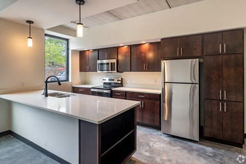 A kitchen with a white counter top and a stainless steel refrigerator.