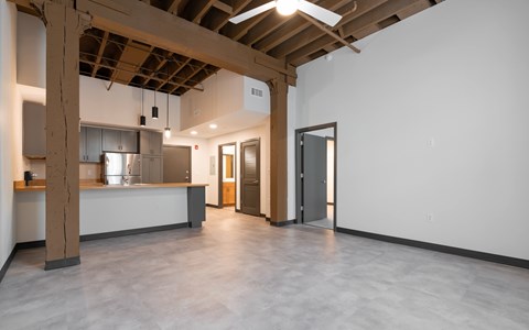 A large open space with a kitchen area and a doorway leading to another room.