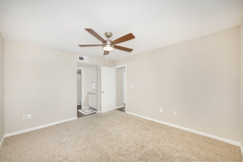 A room with a ceiling fan and carpeted floor.