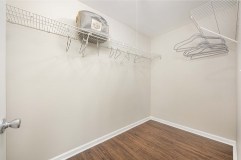 A white closet with a white door and a white wire shelf with a bag on it.