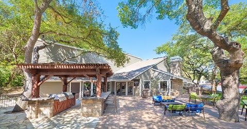 A building with a patio and trees in front.