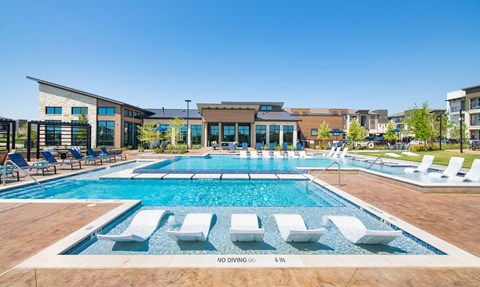 a swimming pool with lounge chairs and a building in the background