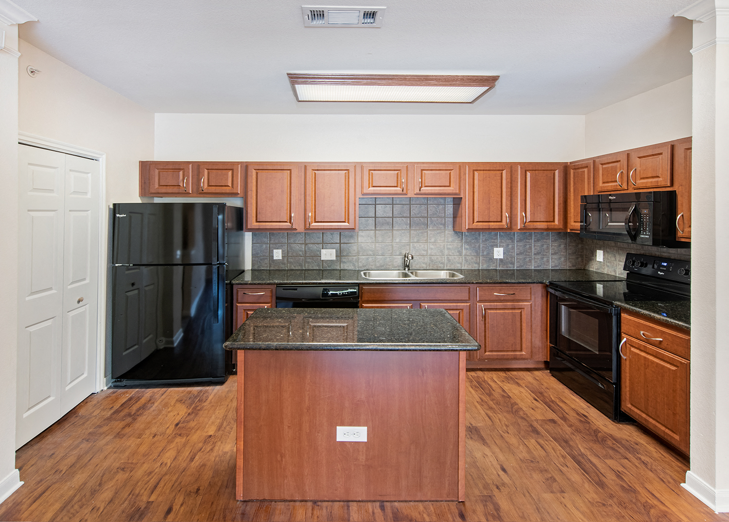 A kitchen with wooden cabinets and black appliances.