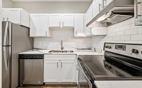 a white kitchen with stainless steel appliances and white cabinets